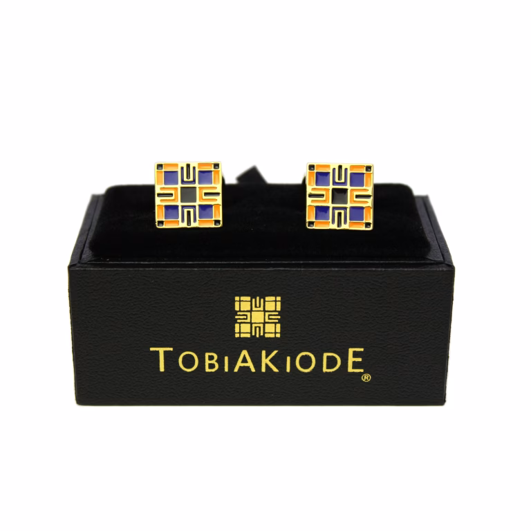 TobiAkiode cufflinks in gold tone with the black-corner geometric logo, boxed front view